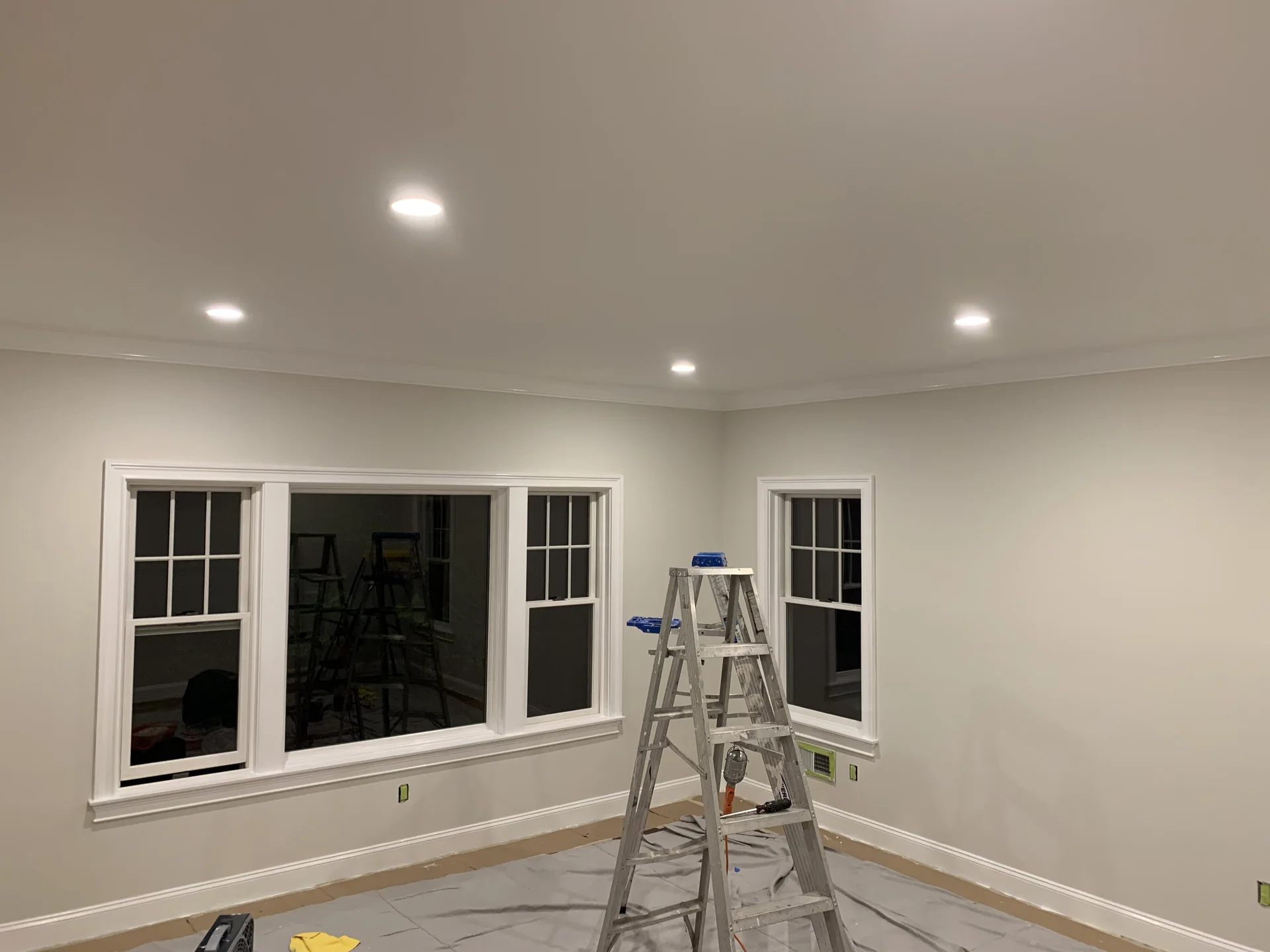 Residential interior painting project showing painted walls, ceiling, windows and protected flooring