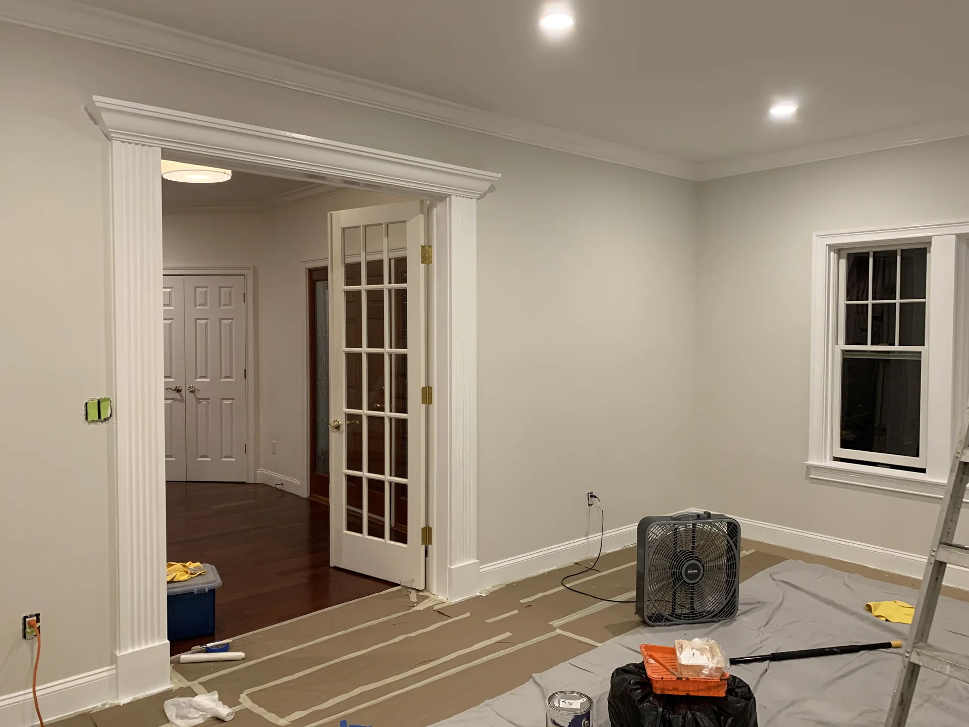Residential interior painting project showing walls, doorway trim and protected flooring